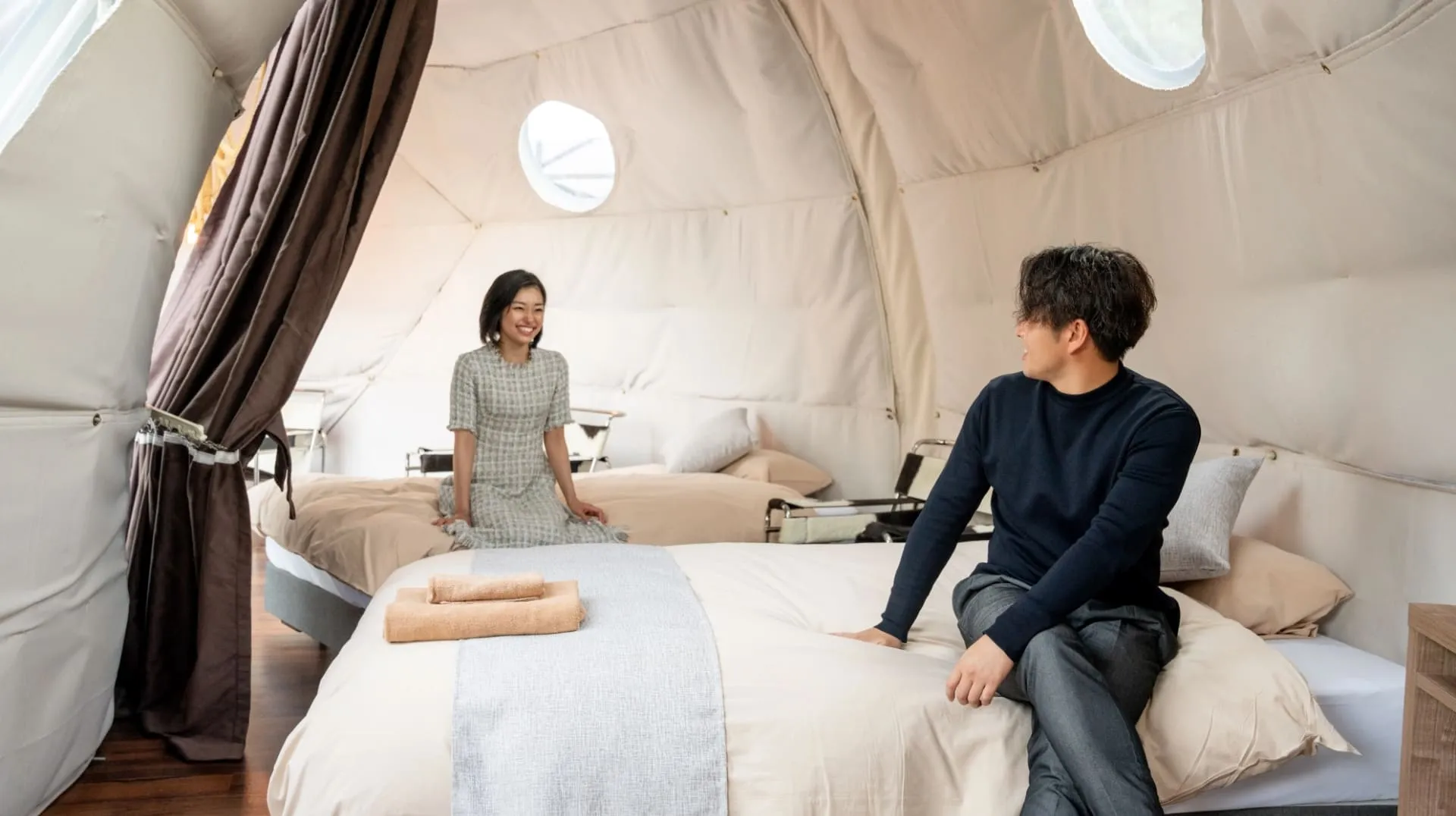 デュラクスアウトドアリゾート京丹後久美浜LABOのドーナツ型テントの室内に座る男女2人の写真